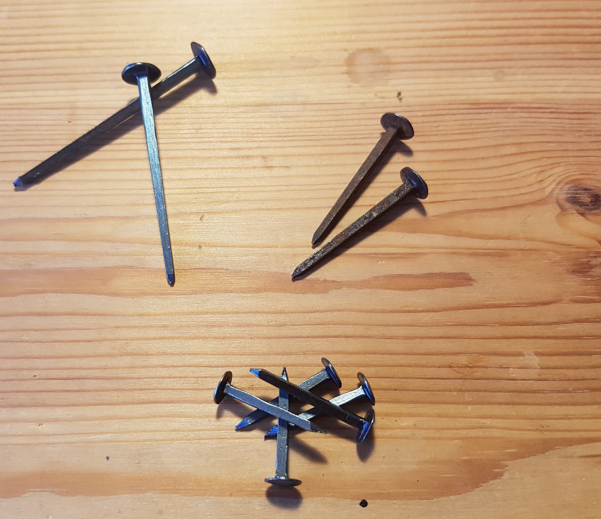 Drie maten gesmede nagels naast elkaar