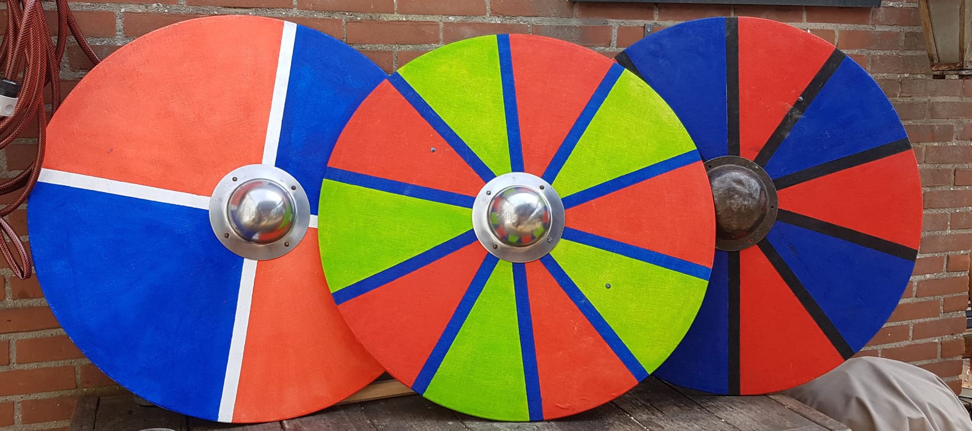Drie beschilderde Vikingschilden in rood, blauw en groen